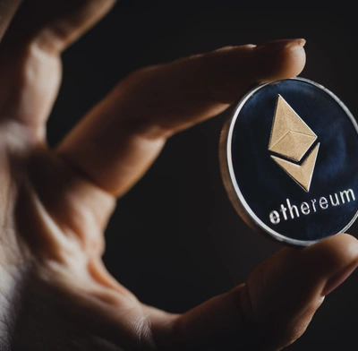 Hand holding a physical depiction of an Ether token
